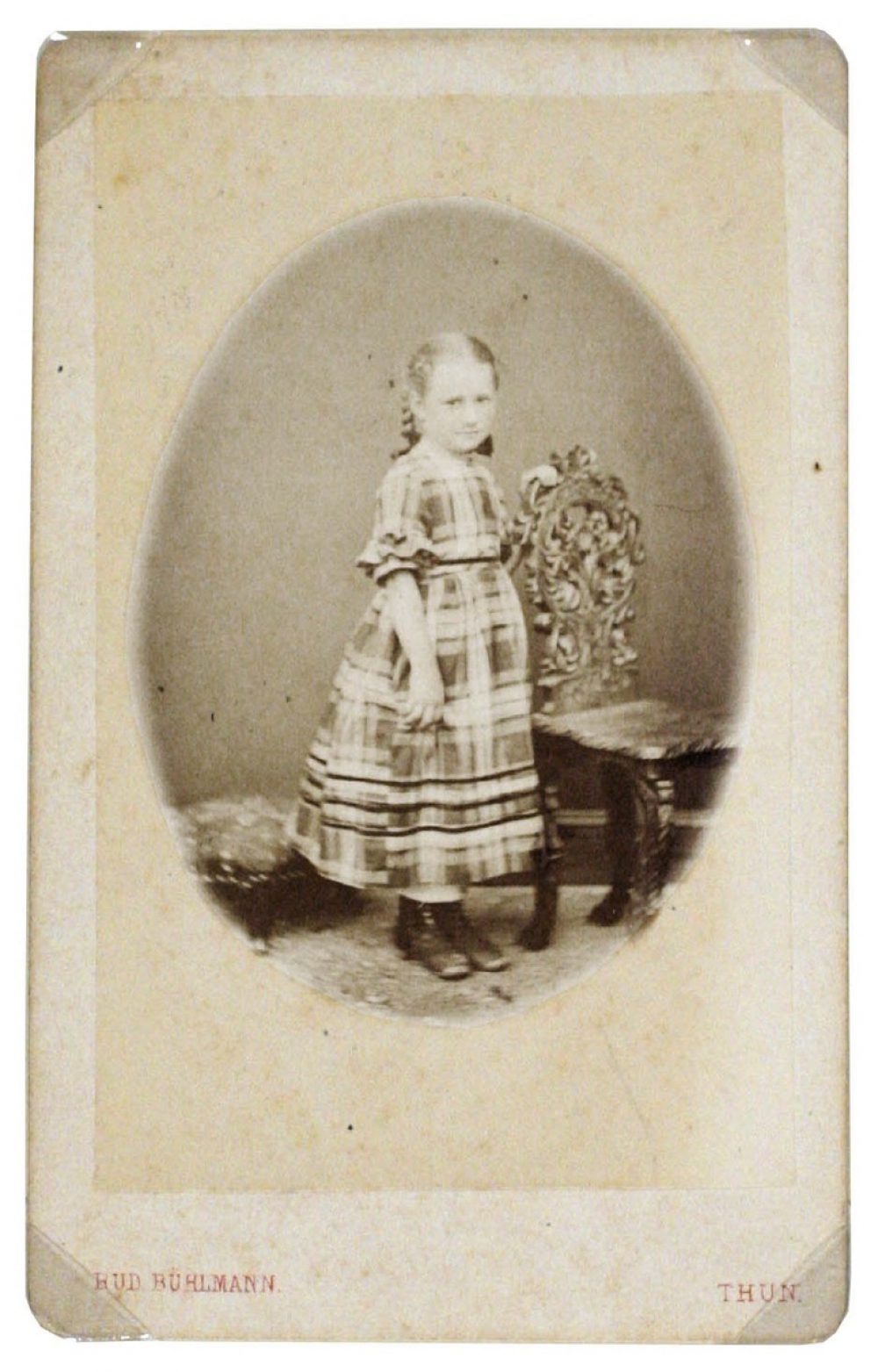 Fillette appuyée à un fauteuil. 