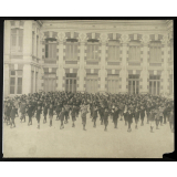 Garçons alignés dans la cours d'un bâtiment scolaire. 