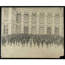 Garçons alignés dans la cours d'un bâtiment scolaire. 