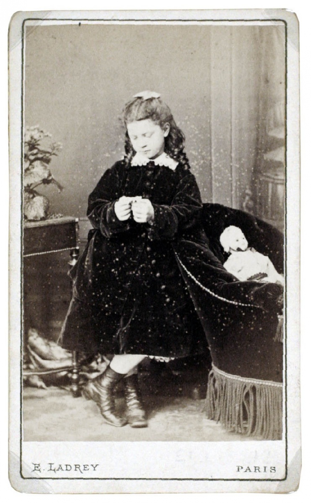 Petite fille pensive à la poupée et au fauteuil crapaud. 