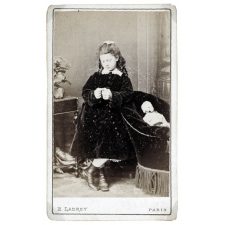 Petite fille pensive à la poupée et au fauteuil crapaud. 