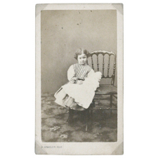 Petite fille à la poupée, s'appuyant à une chaise. 