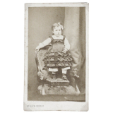 Petite fille se tenant debout sur un repose-pied et un fauteuil. 