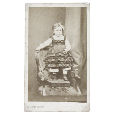 Petite fille se tenant debout sur un repose-pied et un fauteuil.