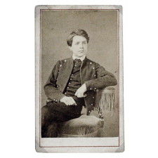 Portrait de Paul Bouget en costume, assis. 