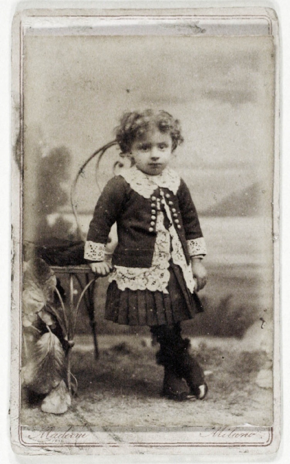 Petite fille s'appuyant à une chaise. 