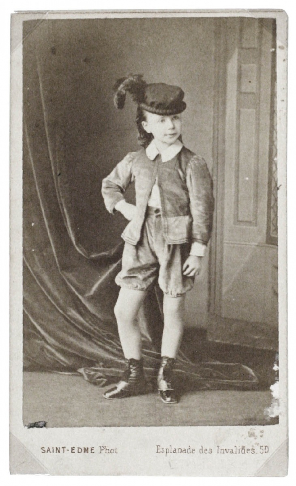 Fillette en habit de garçon et chapeau à plume. 