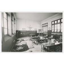 Ecole maternelle. La classe des tout petits : tapis et coussins avec jeux de volumes; tables plates avec jouets et constructions simples; corbeilles à cubes. Air, lumière et chauffage central.