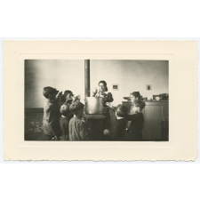 Voilà l'heure de la soupe... Et la souriante institutrice distribue aux petits paysans affamés le bouillon qui, pendant la classe du matin, a tout simplement cuit sur le poële. Pas de matériel, pas de frais, mais des résultats avec un peu de dévouement et de bonne humeur.