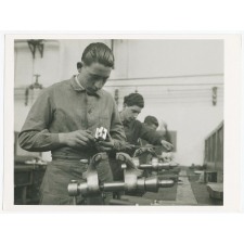 A l'atelier. L'apprenti vérifie un ajustage difficile qu'il tient à terminer. Ecole d'apprentissage d'Alsthom St-Ouen.
