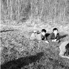 Ecole Freinet, classe promenade : deux garçons couchés dans l'herbe, l'un écrivant sur une feuille.