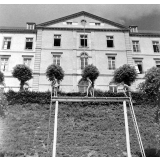 Lycée de Coutances : la façade sur les jardins. Trois élèves effectuent des exercices physiques.