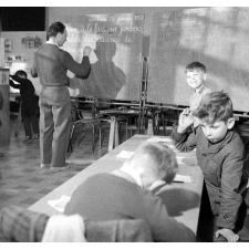 Méthode Freinet : l'apprentissage de l'imprimerie et la réalisation d'un journal scolaire. Le maître rédige un texte au tableau noir ; les élèves ont des activités diverses.