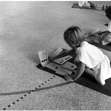 Enseignement musical et initiation rythmique, école maternelle : des élèves, sur des tapis de sol, utilisent des notes de musique en carton.