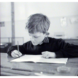 Ecole primaire. Un élève appliqué écrit des mots sur son cahier.