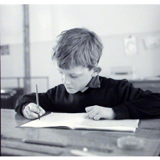 Ecole primaire. Un élève appliqué écrit des mots sur son cahier.