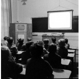 Enseignement audiovisuel : un écran déroulé dans une classe. La présence d'un téléviseur intégré dans une armoire. 