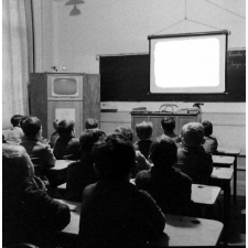 Enseignement audiovisuel : un écran déroulé dans une classe. La présence d'un téléviseur intégré dans une armoire.