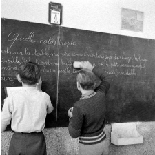 Méthode Freinet : l'apprentissage de l'imprimerie et la réalisation d'un journal scolaire. Deux élèves écrivent un texte au tableau noir.