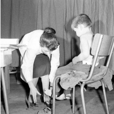 Visite médicale (cabinet mobile) à l'école primaire de Labruguière. Une infirmière déchausse un élève.