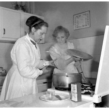 Collège d'enseignement technique pour jeunes filles. Le cours de cuisine. Le professeur encadre une élève.