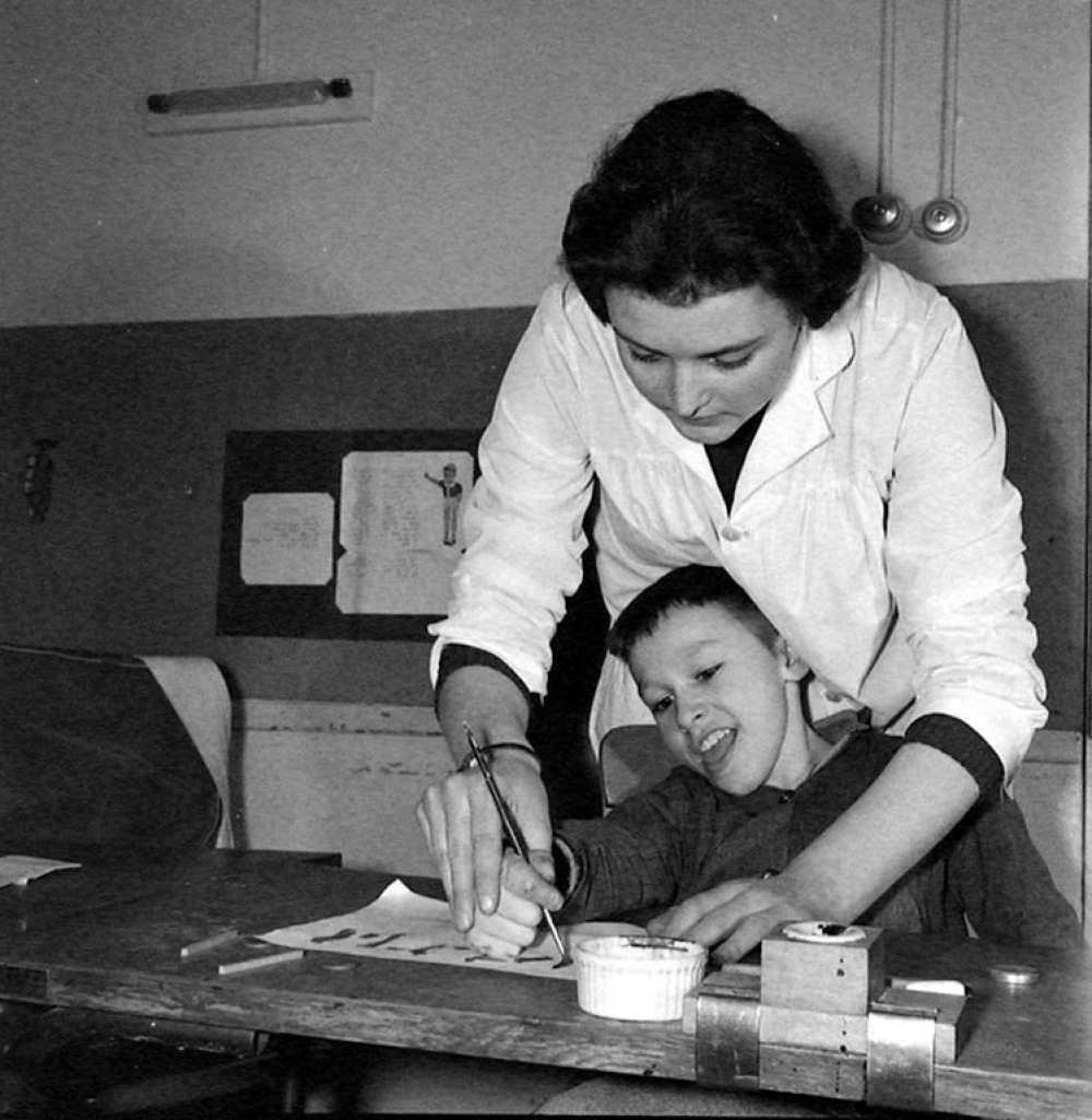 Centre de réadaptation fonctionnelle : un élève apprend à peindre, sous contrôle de son éducatrice.
