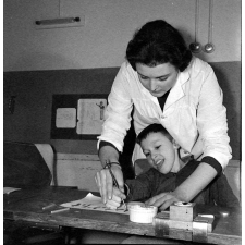 Centre de réadaptation fonctionnelle : un élève apprend à peindre, sous contrôle de son éducatrice.