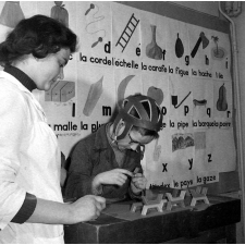 Centre de réadaptation fonctionnelle : un élève procède à des assemblages (la rééducation des mains et des doigts). En arrière-plan, apprentissage de la lecture.