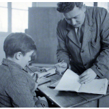 Ecole primaire. L'instituteur vérifie le cahier d'un élève.