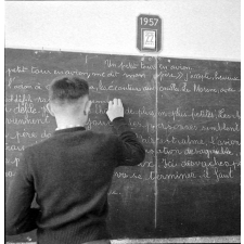 Méthode Freinet : l'apprentissage de l'imprimerie et la réalisation d'un journal scolaire. Un élève écrit un texte au tableau noir.