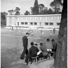 Centre d'éducation surveillée : la détente. Des jeunes sur un banc, d'autres disputant un match de football.