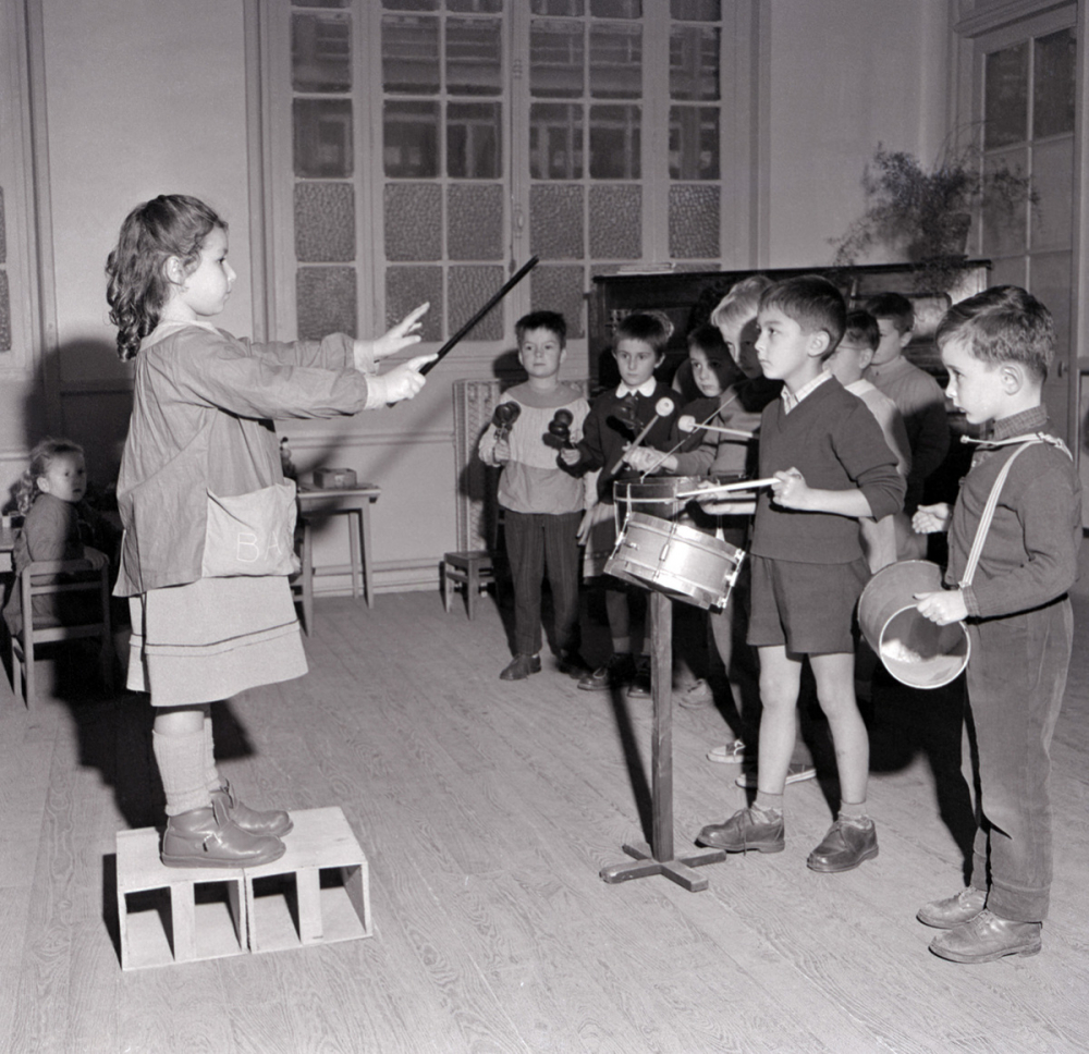 Enseignement musical. Une fillette dirige un orchestre d'écoliers de maternelle.