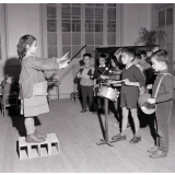 Enseignement musical. Une fillette dirige un orchestre d'écoliers de maternelle.