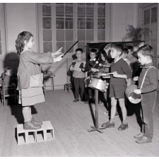 Enseignement musical. Une fillette dirige un orchestre d'écoliers de maternelle.
