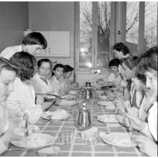 Collège d'enseignement technique pour jeunes filles. Le cours de cuisine. Le professeur et les élèves goûtent les plats préparés.