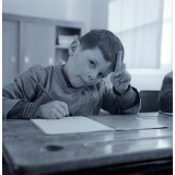Ecole primaire. Un élève écrit lettres et syllabes.