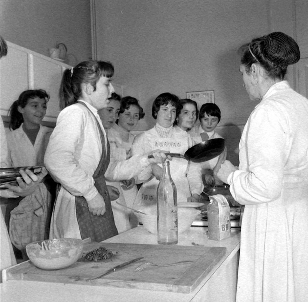 Collège d'enseignement technique pour jeunes filles. Le cours de cuisine. L'art du maniement de la poêle pour les crêpes.