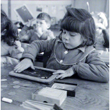 Ecole primaire. Une élève efface son ardoise à la main.