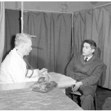 Visite médicale (cabinet mobile) à l'école primaire de Labruguière. Le médecin s'entretient avec l'instituteur au sujet du comportement et des résultats des élèves.