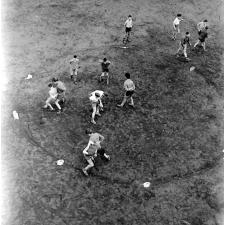 Pratique du sport sur un stade parisien : les élèves, sous la surveillance du professeur, effectuent exercices et jeux par groupes de deux.