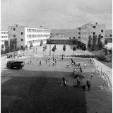 Architecture scolaire : vue sur l'Ecole nationale d'enseignement technique. Les bâtiments principaux, la cour, les terrains de sport. Travaux de goudronnage des terrains de sports collectifs.