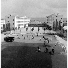 Architecture scolaire : vue sur l'Ecole nationale d'enseignement technique. Les bâtiments principaux, la cour, les terrains de sport. Travaux de goudronnage des terrains de sports collectifs.