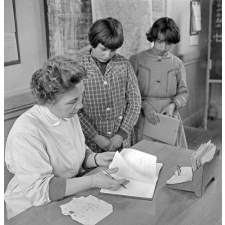Ecole primaire, classe de Madame Hardy : l'institutrice vérifie les cahiers de poésie de deux élèves.