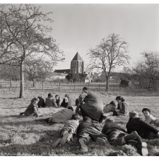 Ecole Freinet, classe promenade : les élèves, couchés sur l'herbe, observent et rédigent, guidés par leur maître.